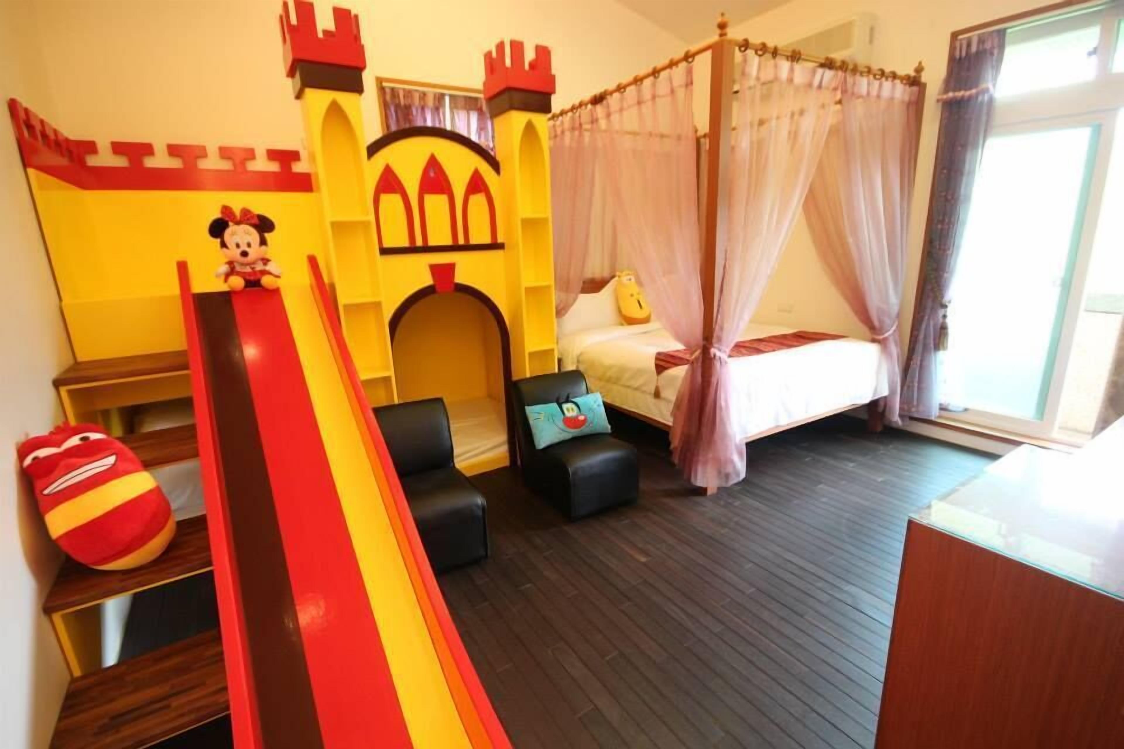 Un espace de jeux pour enfants avec un toboggan, une structure de jeu en forme de château et un lit à baldaquin.