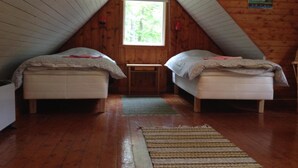 A small, cozy attic bedroom with two beds, a wooden ceiling, and a window providing natural light. - Marston Hill (Mullsjö)