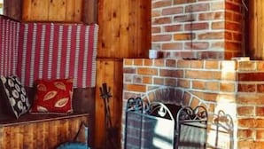 A cozy room with a brick fireplace, wooden walls, and a bench with cushions. - Marston Hill (Mullsjö)