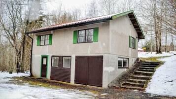Una casa de dos pisos con techo inclinado, contraventanas verdes y una puerta marrón.