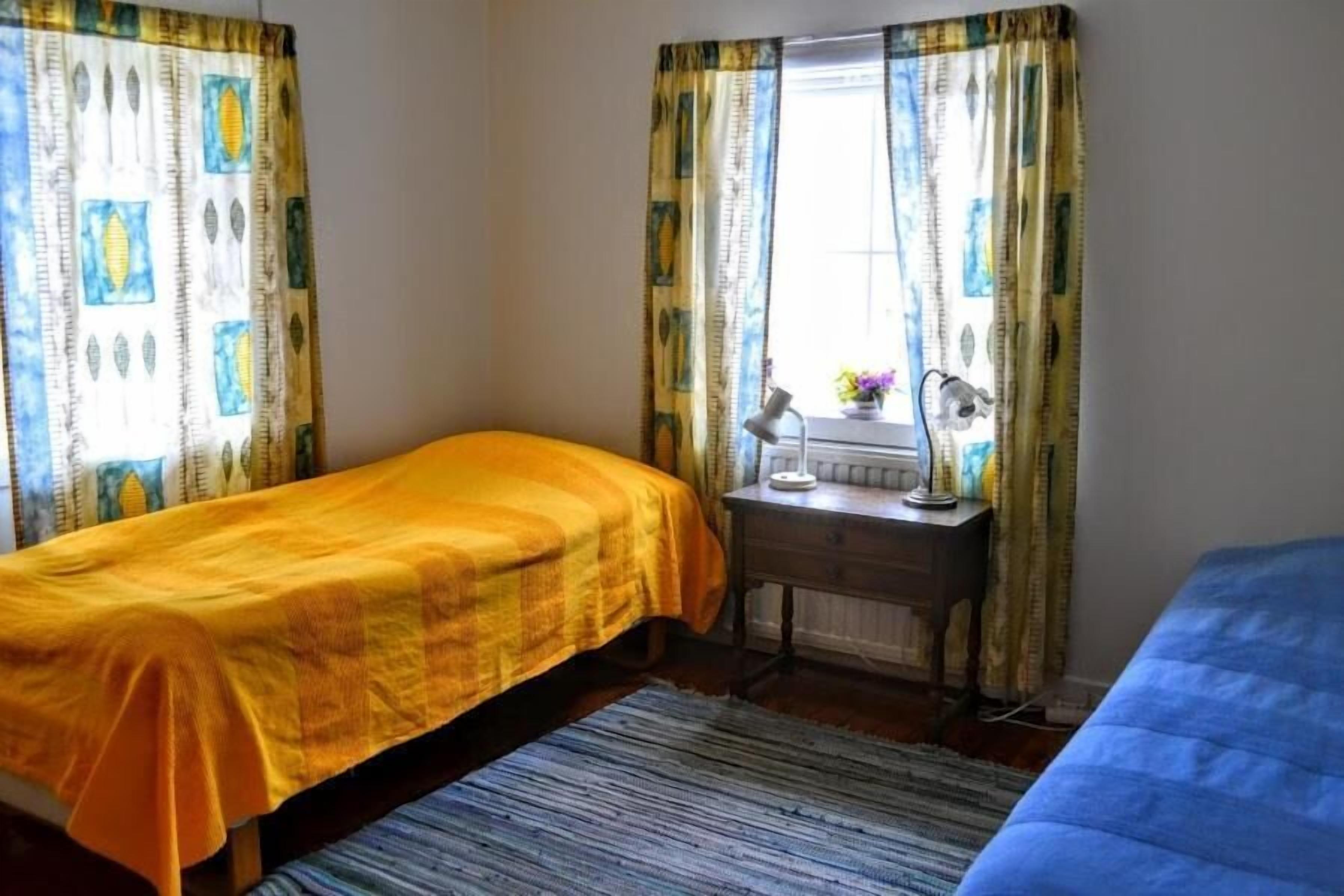 Un dormitorio con dos camas, un escritorio pequeño con lámpara y una ventana con cortinas.