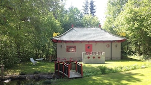 A small building with a tiled roof, surrounded by lush greenery. - Marston Hill (Mullsjö)