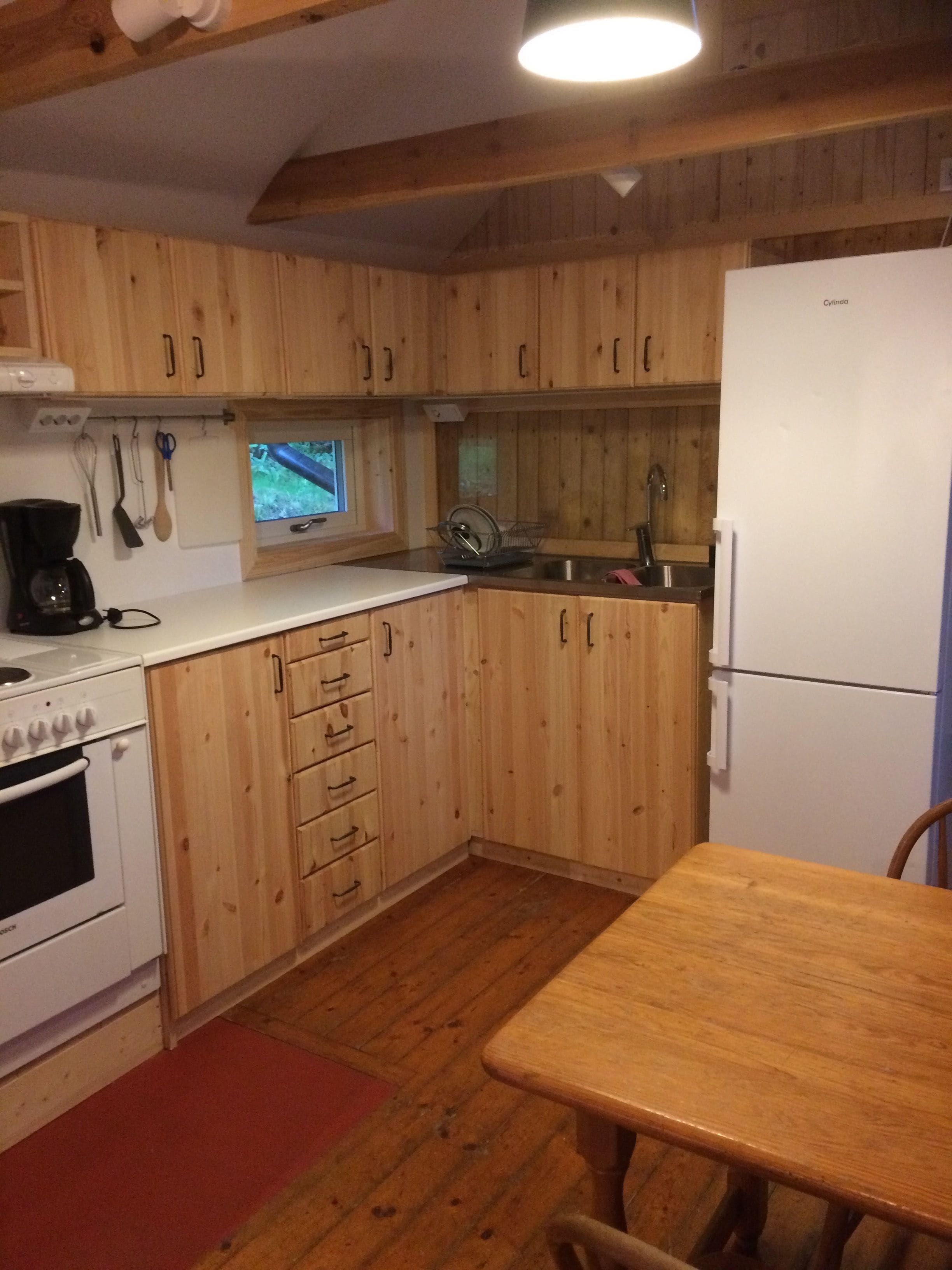 Une cuisine avec des meubles de rangement en bois, une cuisinière blanche, un évier et un réfrigérateur.
