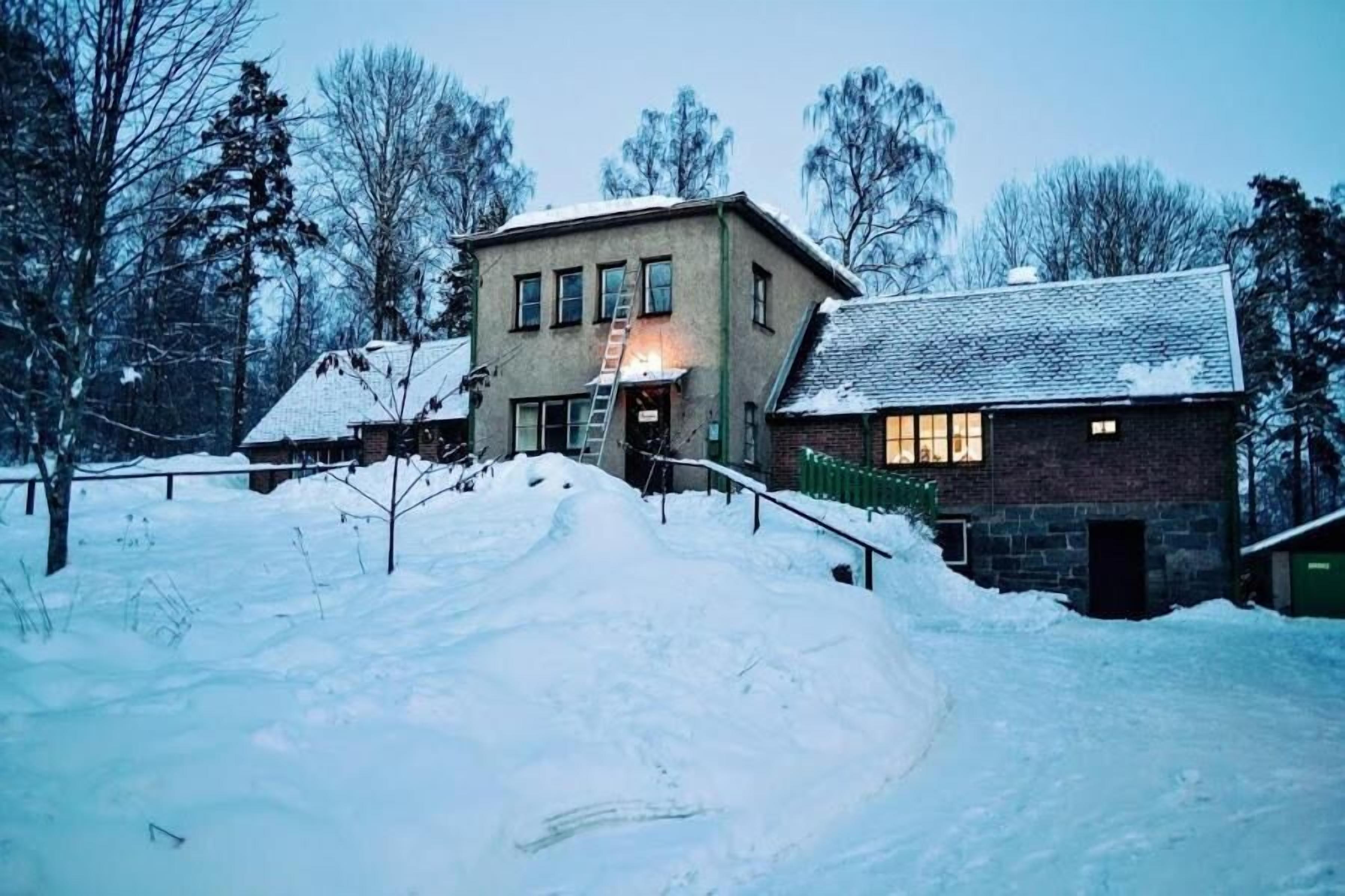 A two-story building with a snow-covered roof and a visible staircase leading to the entrance.