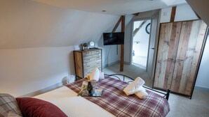A bedroom with a bed, a dresser, a television, and a large mirror. - Charming New Forest Escape Near Forest Walks & Coast (Fordingbridge)