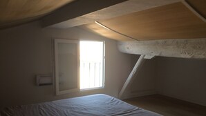 Una habitación con cama, ventana y techo inclinado.