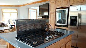 A modern kitchen with a central island stove, stainless steel appliances, and wooden cabinetry. - Large, safe, WATERFRONT home in Idyllic setting with kayaks, bikes, &GARAGE use. (Reedville)