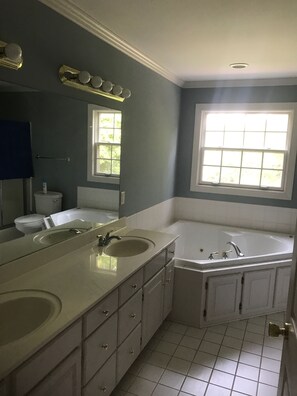 Een bad/douchecombinatie, een bubbelbad, een haardroger, handdoeken