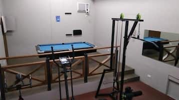 A gym with exercise equipment, a pool table, and a mirror.
