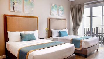A hotel room with two beds, a balcony, and artwork on the walls.