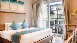 A hotel room with a large bed, a balcony with outdoor seating, and a view of the building outside. - Royale Parc Hotel Tagaytay (Tagaytay)