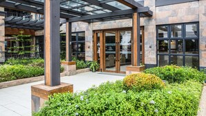 A modern building entrance with glass doors, stone facade, and a covered outdoor area with plants. - Royale Parc Hotel Tagaytay (Tagaytay)