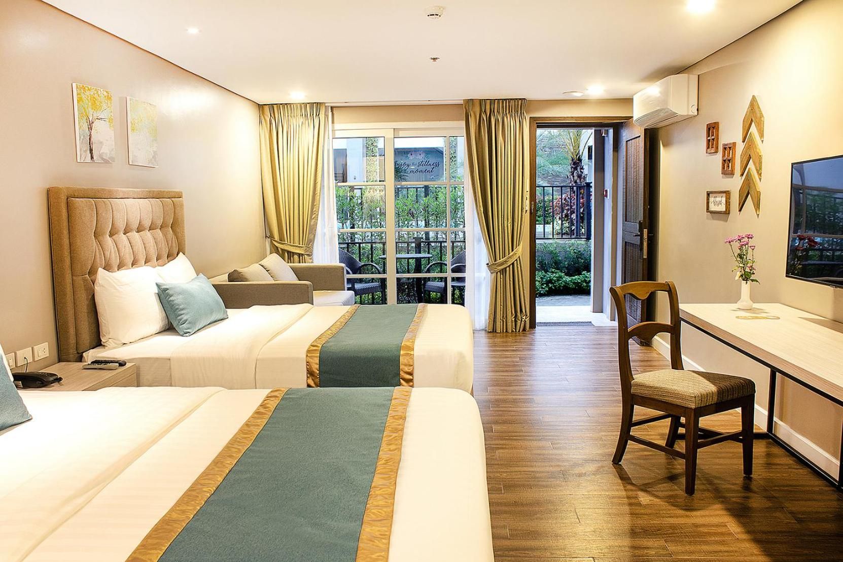 Ein Hotelzimmer mit zwei Betten, einem Schreibtisch, einem Stuhl und einem großen Fenster mit Vorhängen.