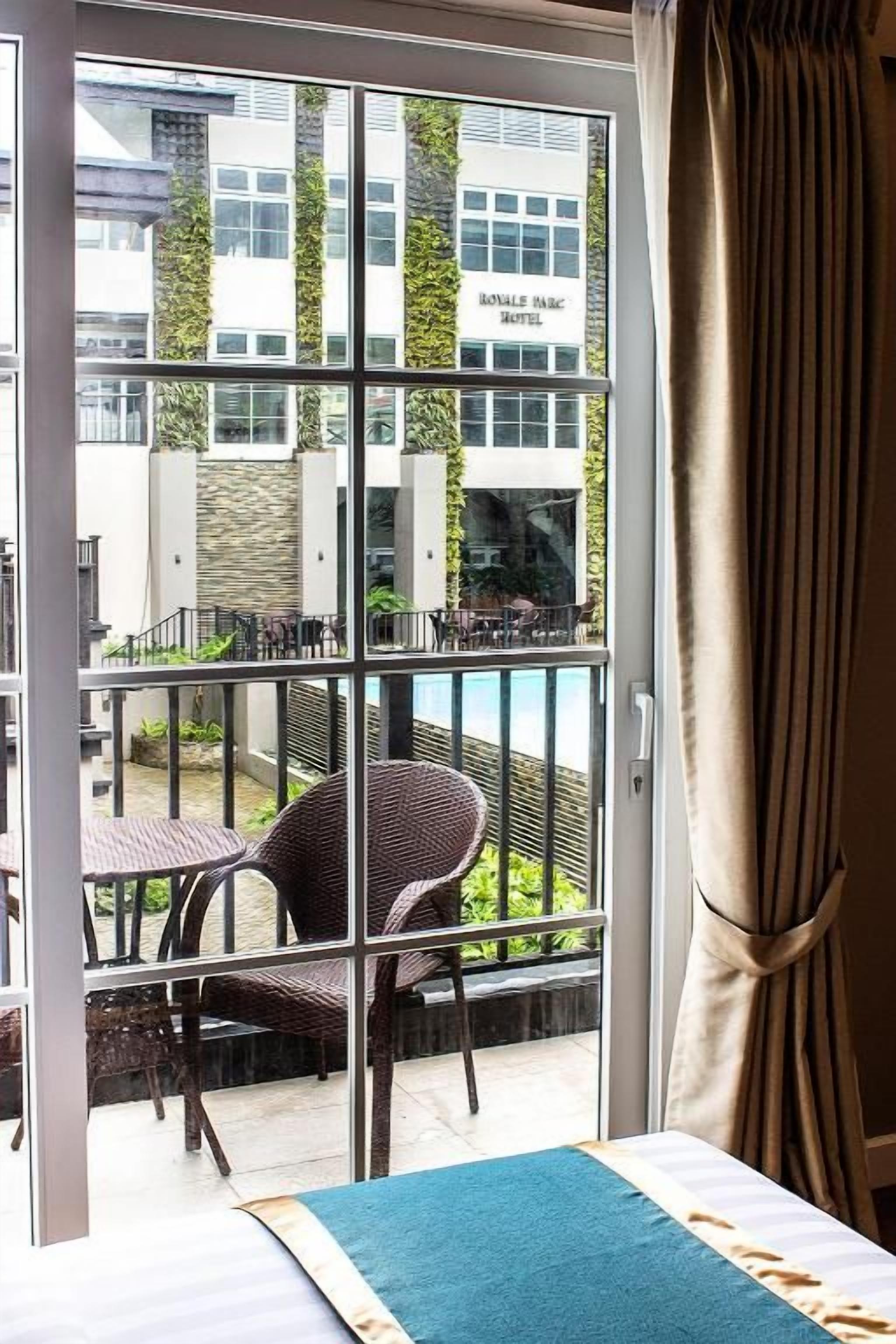 A hotel room with a sliding glass door leading to an outdoor seating area with wicker chairs and a table.