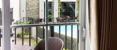 Hotellihuone, jossa on liukuovet, jotka johtavat ulkotilaan, jossa on rottinkituoleja ja pöytä.