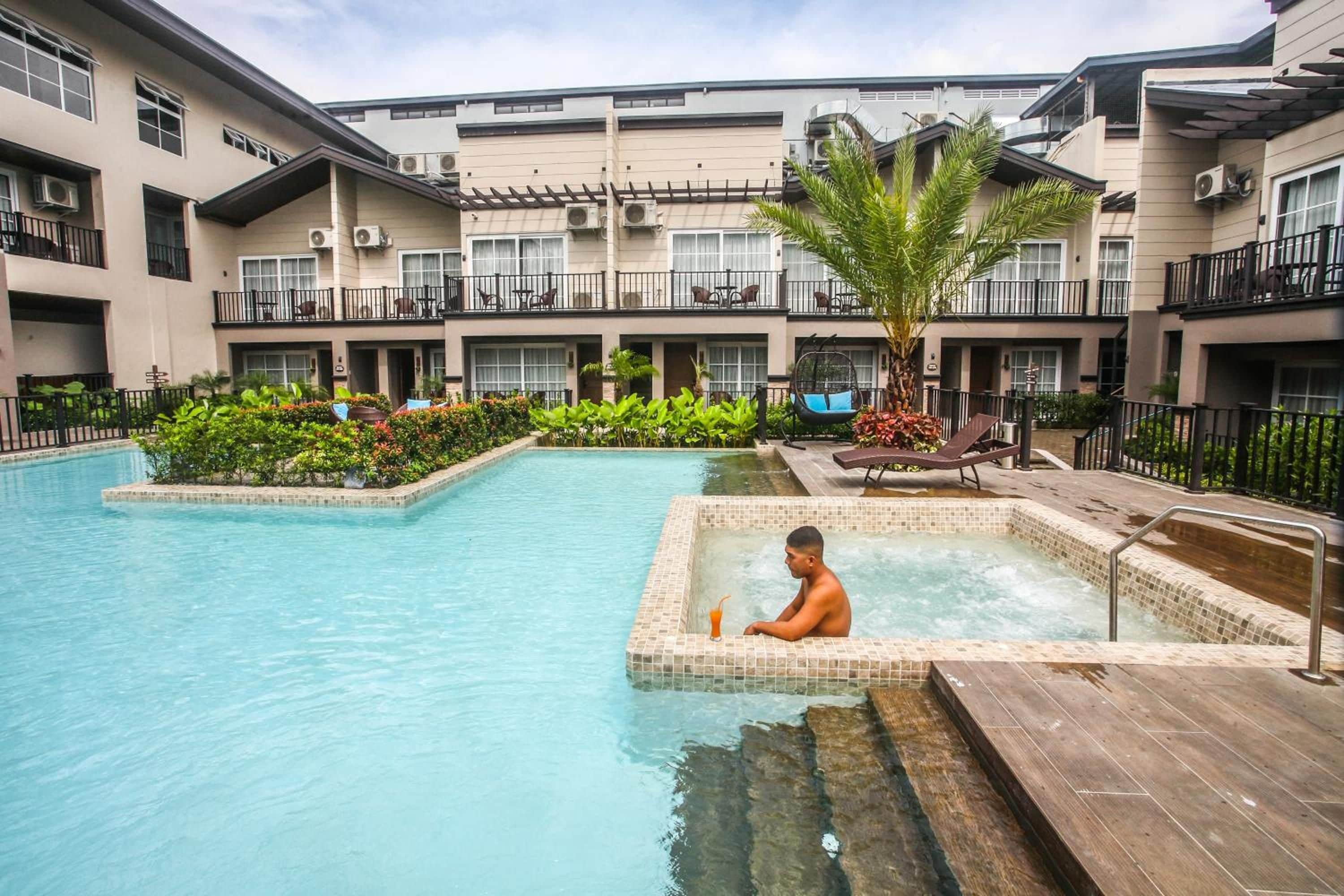 A hotel with a swimming pool, a hot tub, and a patio area with outdoor seating.