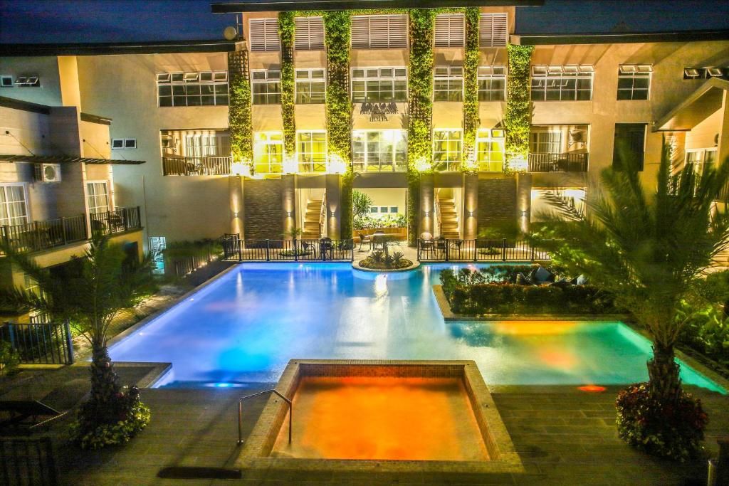 A hotel with a swimming pool, multiple balconies, and a well-lit exterior.