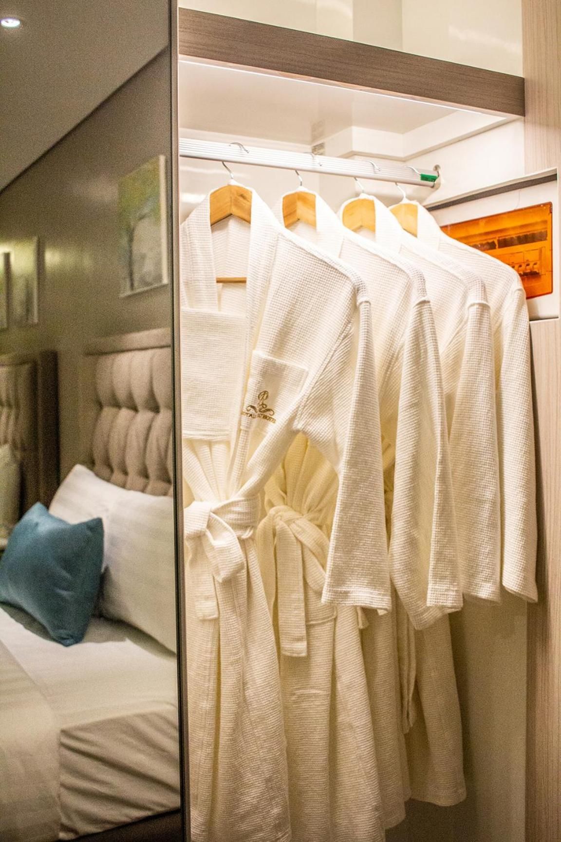 A hotel room with a bed, a hanging robe rack, and a mirror.