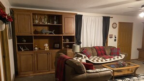A cozy living room with a brown sofa, a wooden cabinet, a coffee table, and a patterned rug. - A Home With Room to Roam (Omak)