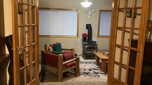 A cozy living room with a fireplace, a wooden door, and a large window. - A Home With Room to Roam (Omak)