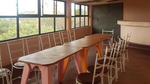 A conference room with a long table and chairs, large windows, and a view of greenery outside. - Sultan Hamud Pyramids Resort (Sultan Hamud)