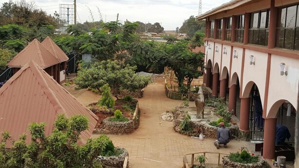A courtyard with a paved walkway, stone walls, and a building with arches and columns. - Sultan Hamud Pyramids Resort (Sultan Hamud)