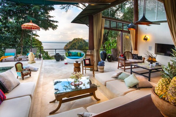 A luxurious outdoor seating area with a pool, comfortable seating, and a view of the ocean.
