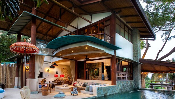 Una villa moderna con piscina, un área de estar cubierta al aire libre y un espacio para comer.