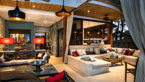 Amplia sala de estar con un sofá grande, una mesa de comedor y un área de bar con vista al exterior.