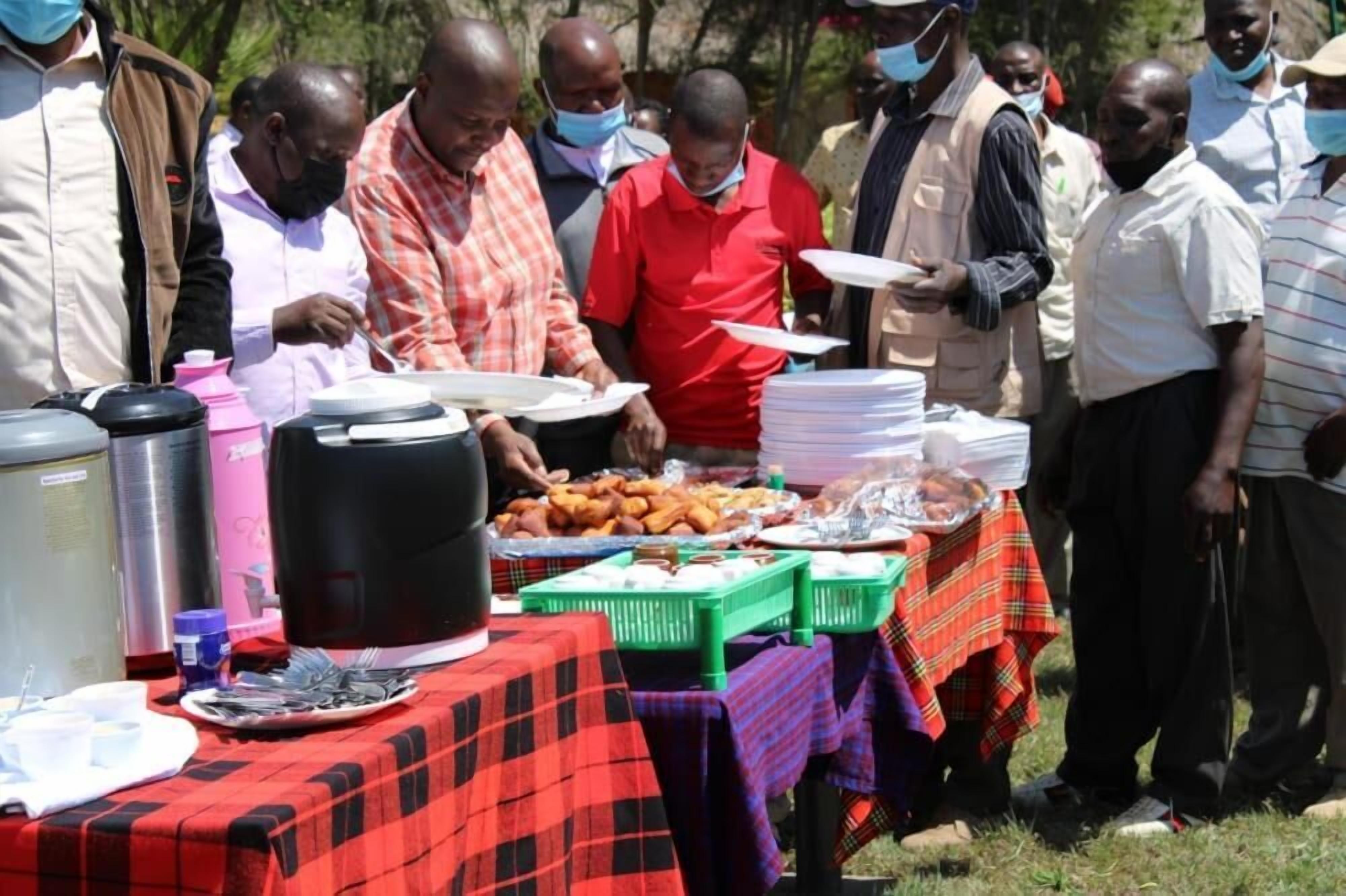A group of people gathered around a buffet table with various food items and serving utensils.