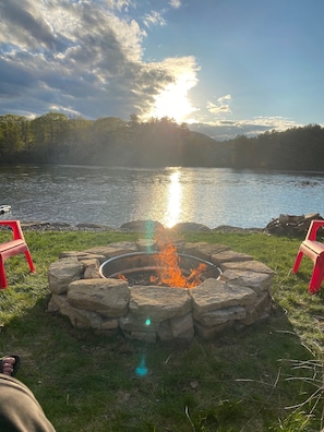 Sit by the fire pit surrounded by serene lake views and a forested hill.
