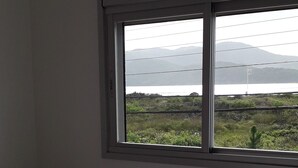 A room with a bed and a window overlooking a landscape with mountains and greenery. - 03 Apartments for Vacation - Morada Madruga - Sea Front, Superior (Praia do Sonho (Ens Brito))