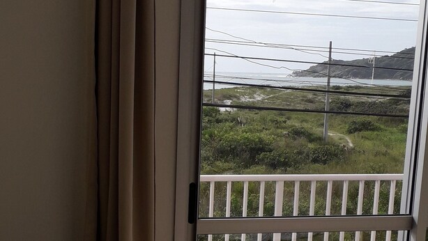 A room with a view through a sliding glass door to a balcony with a white railing. - 03 Apartments for Vacation - Morada Madruga - Sea Front, Superior (Praia do Sonho (Ens Brito))