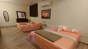 Ein Hotelzimmer mit zwei Betten, Holzboden, einem Spiegel, einer Klimaanlage und einem Flamingo-Bild.