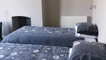 Een slaapkamer met twee bedden, elk voorzien van beddengoed en kussens met een patroon.
