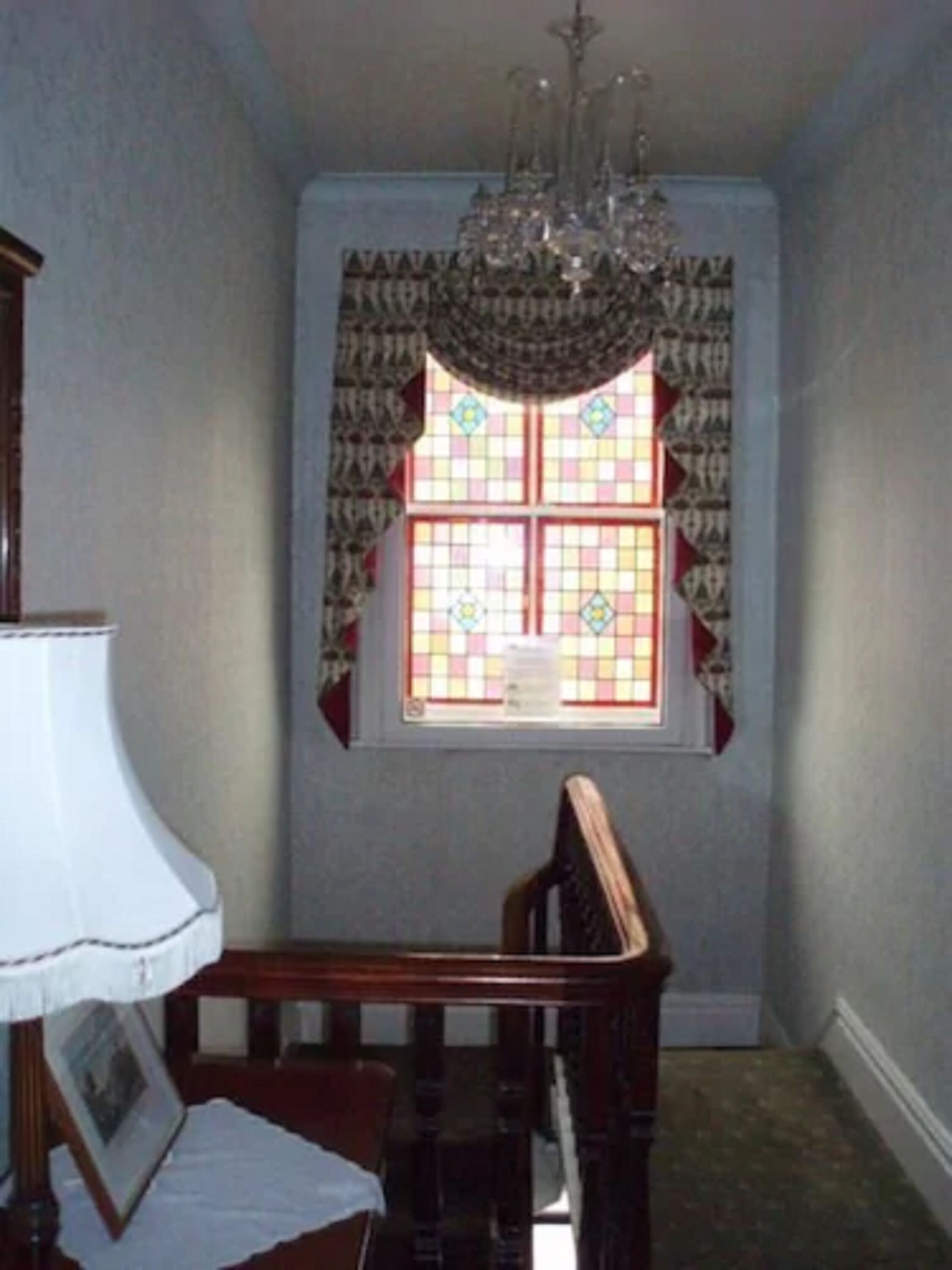 A dining area with a chandelier, a table, and a window with patterned curtains.