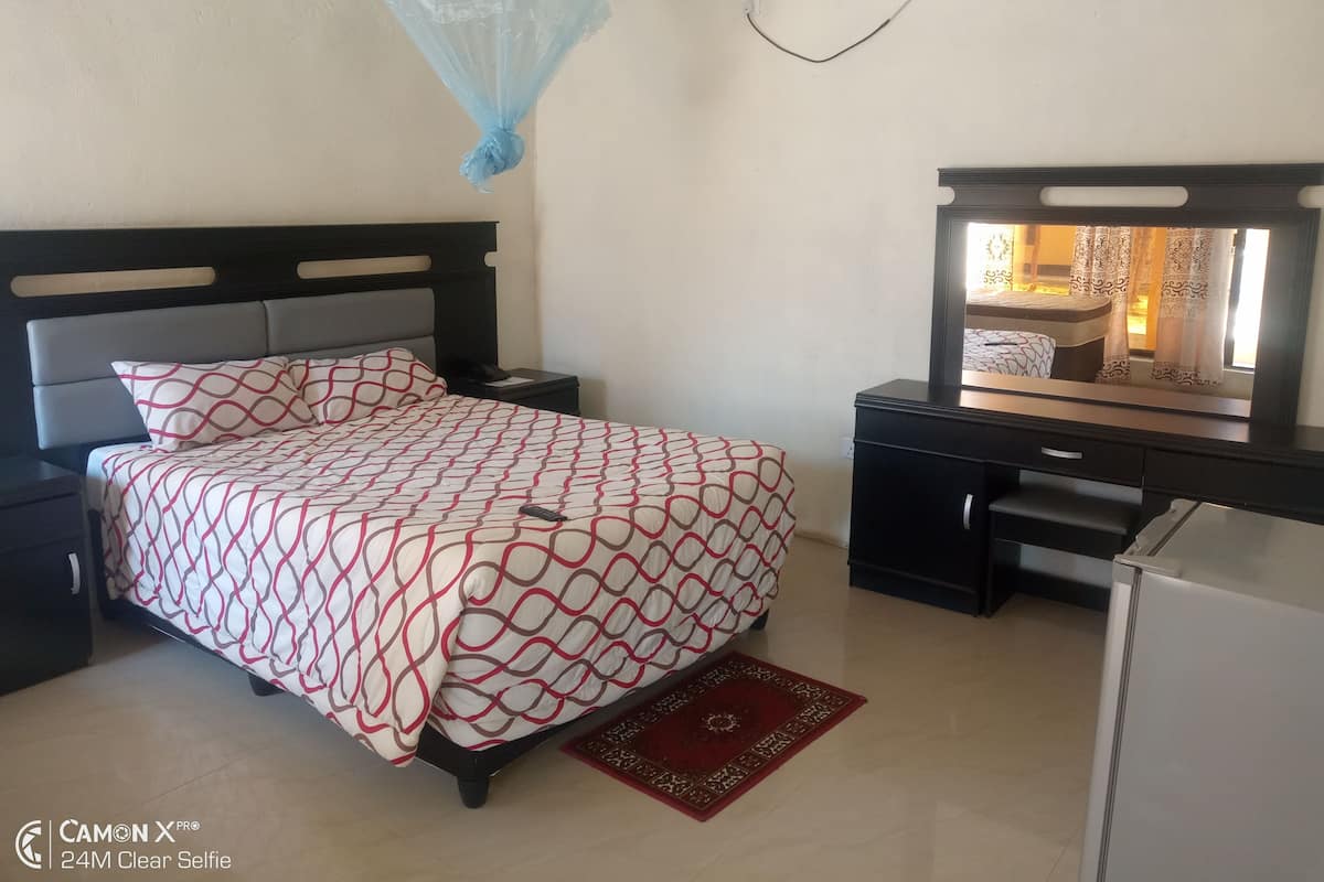 Une chambre à coucher avec un lit, des tables de chevet, un bureau et un téléviseur.