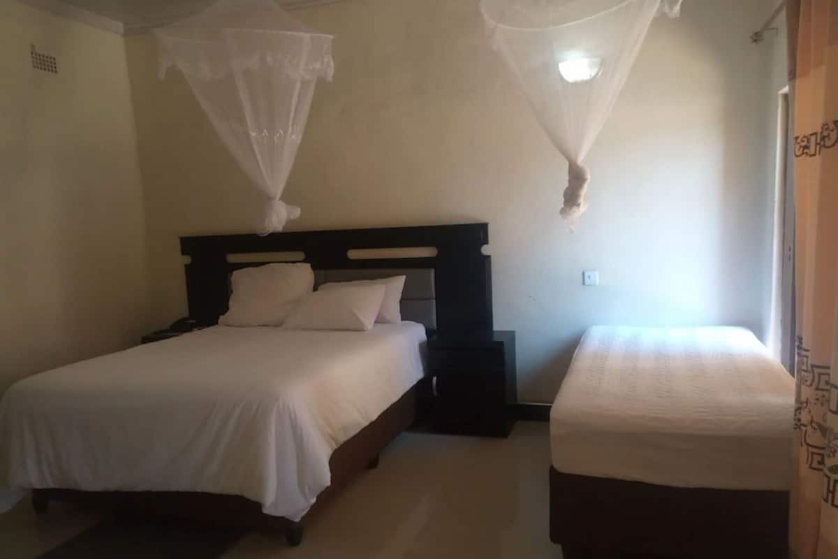 Une chambre avec deux lits, chacun doté de draps blancs et d’une tête de lit en bois. Il y a une table de chevet à côté de chaque lit.