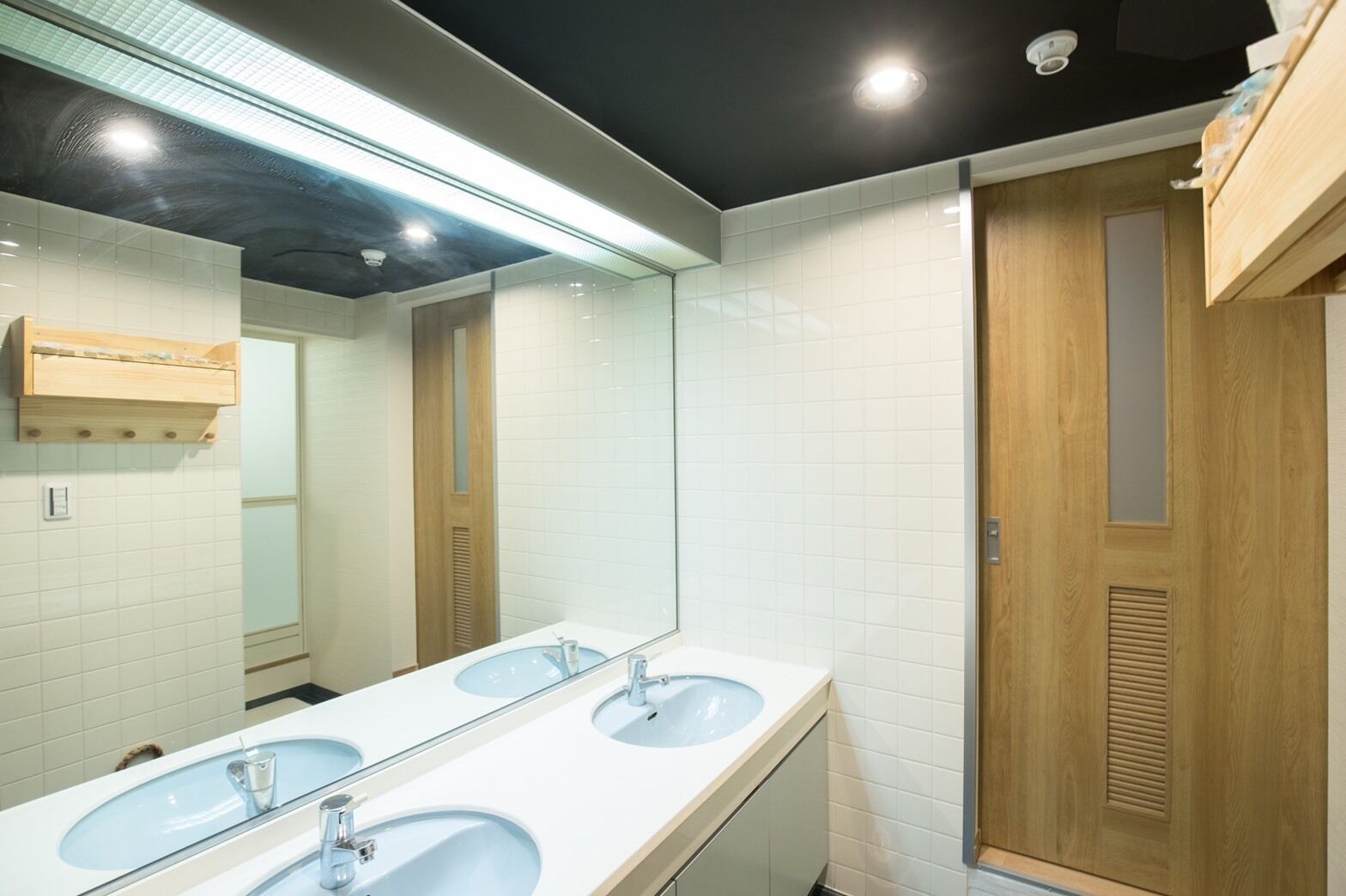 Un bagno moderno con due lavandini, uno specchio grande e porte in legno.