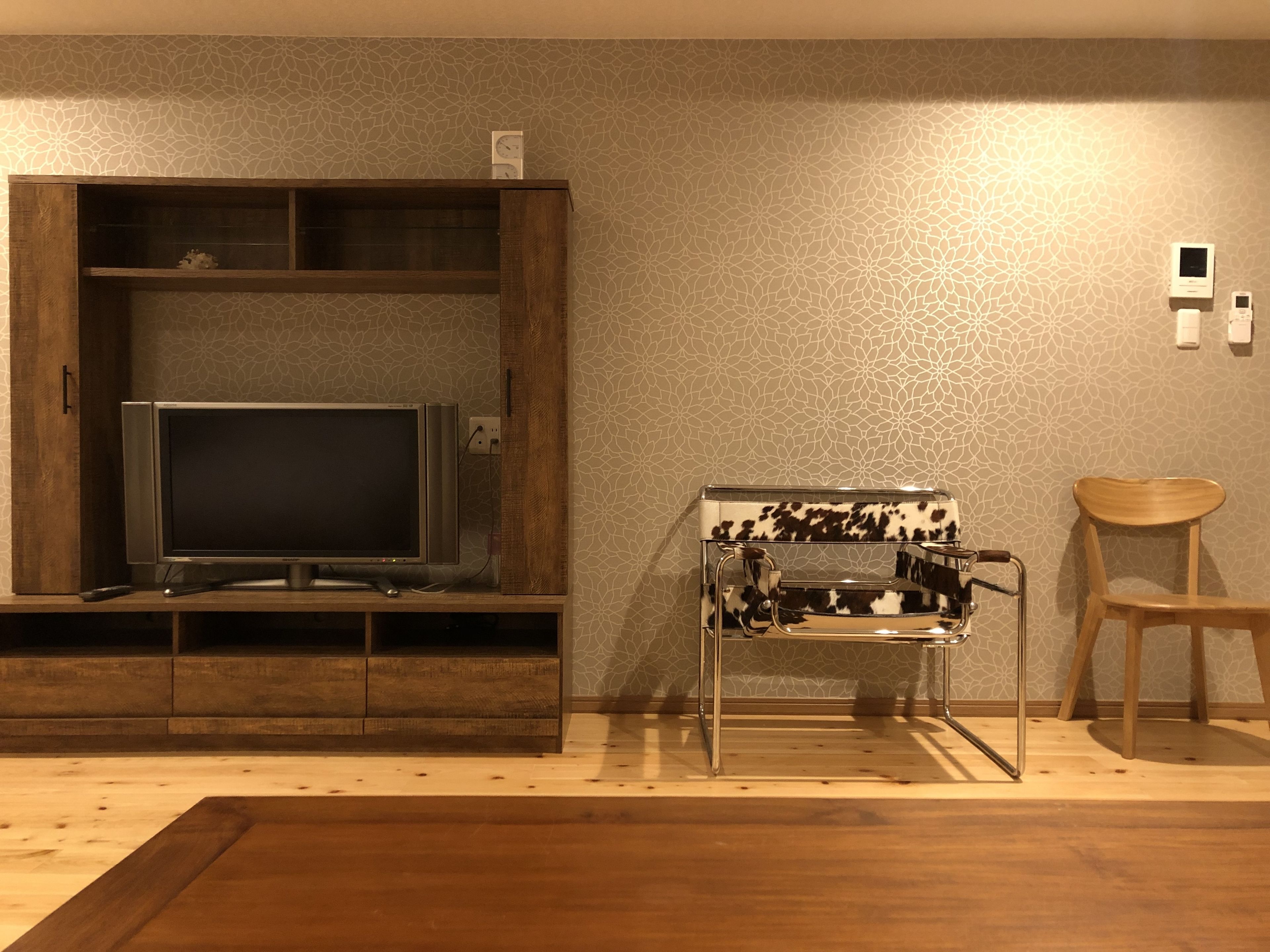 A living room with a flat-screen TV on a wooden stand, a coffee table, and a wooden chair.