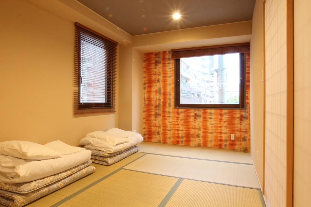 A traditional Japanese room with tatami flooring, a shoji screen, and a futon bed.