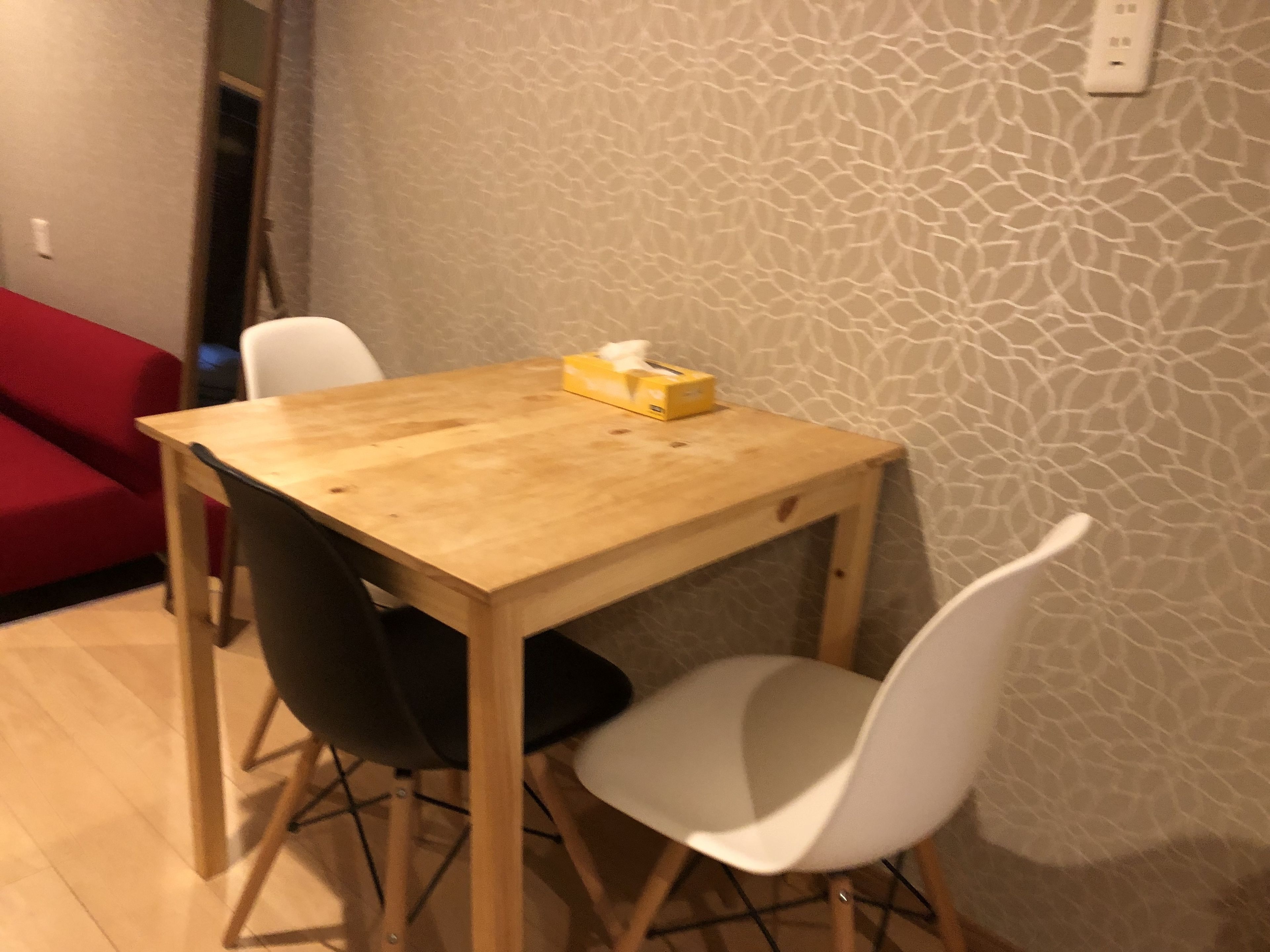 Un pequeño comedor con una mesa de madera y dos sillas blancas.