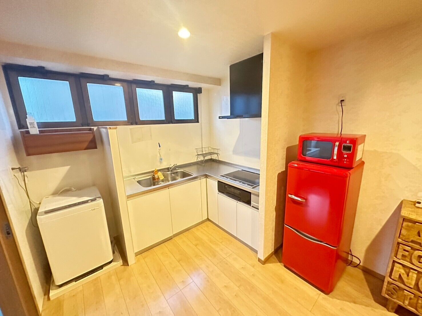 A compact kitchen with a sink, stove, and a red microwave.
