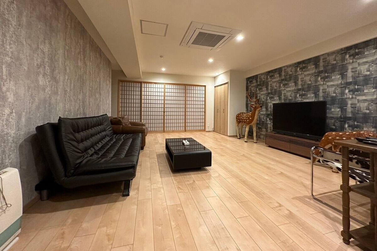 A modern living room with a sofa, coffee table, TV, and a decorative deer statue.
