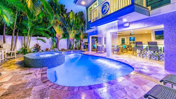 Un espace piscine extérieur moderne, doté d’un jacuzzi, de chaises longues et d’un coin salon abrité.