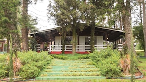 A building with a covered porch, surrounded by lush greenery and a well-maintained garden.