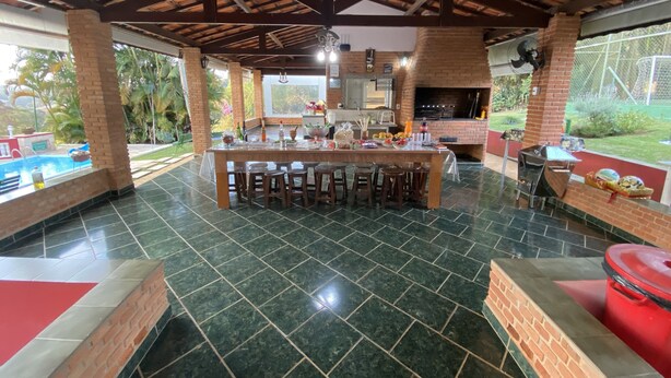 A spacious outdoor kitchen area with a bar, surrounded by a pool and a patio.