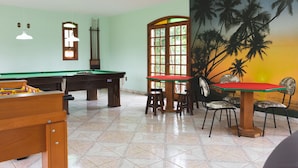 A pool table with a green felt top, a wooden pool table, and a red table with four chairs.