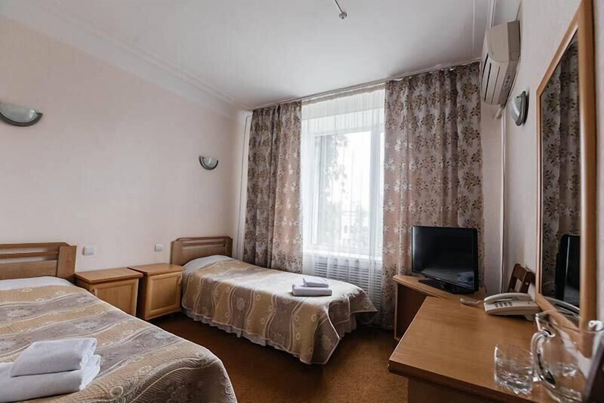 Habitación de hotel con dos camas, televisión, escritorio con teléfono y espejo.