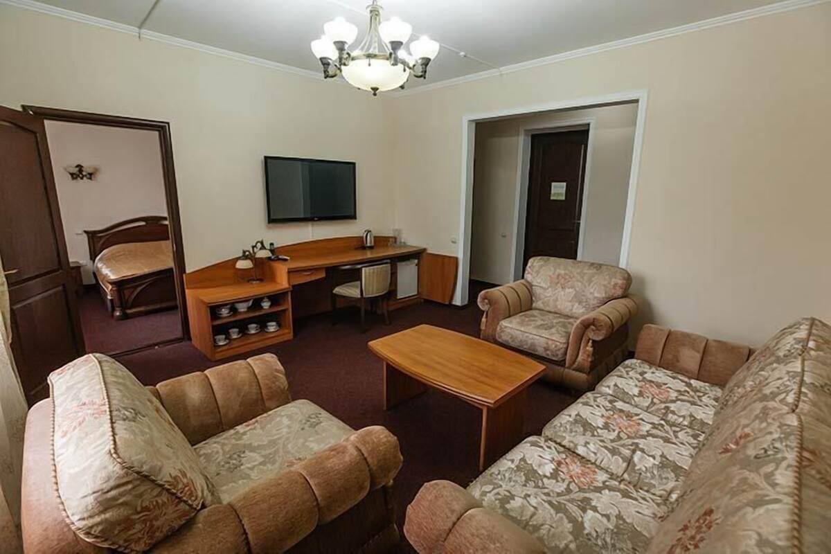 Una sala de estar con un sofá, una mesa de centro de madera, un televisor y un escritorio con una silla.